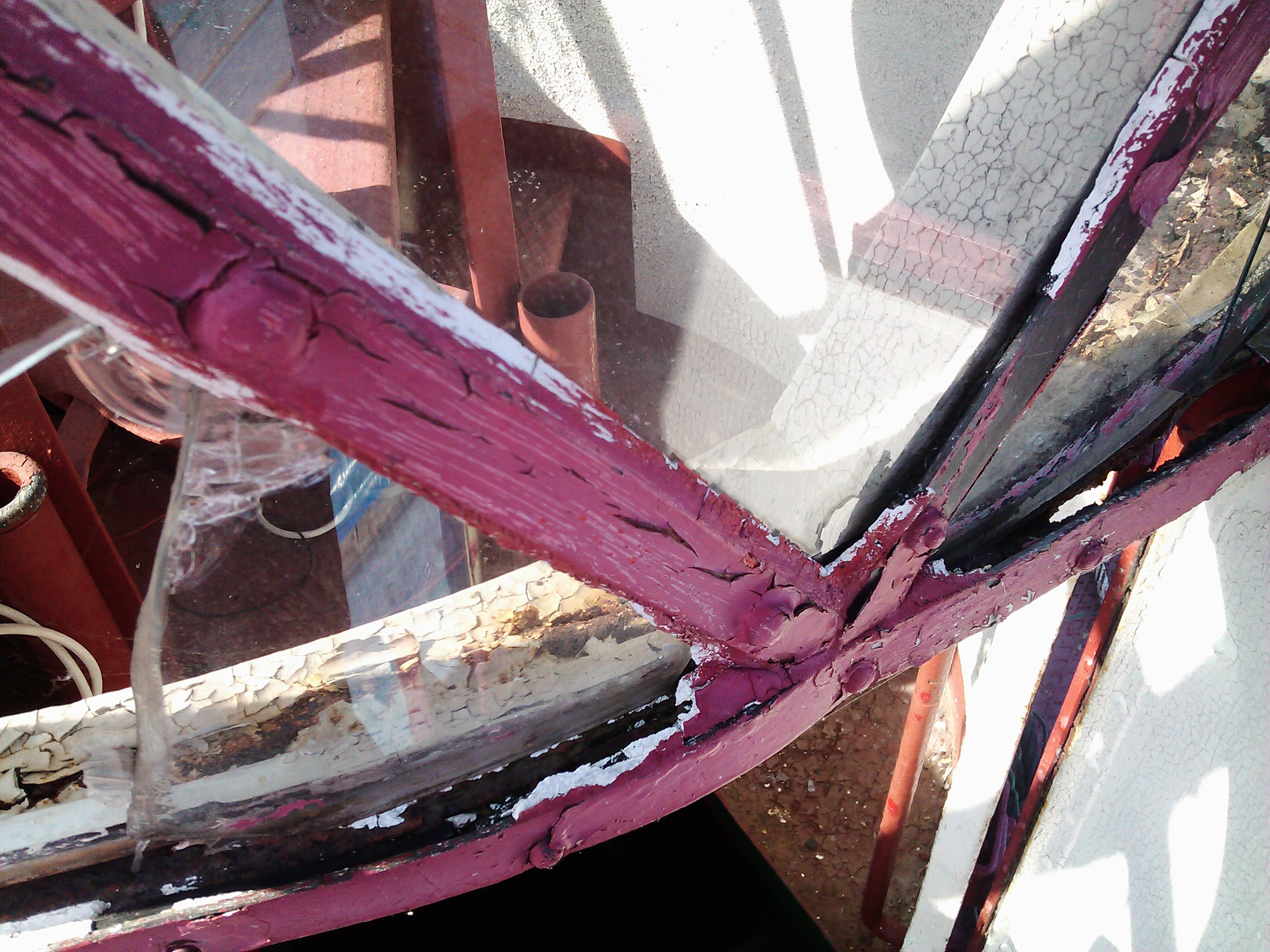 Yksityiskohta ikkunan puitteista. Lasitus rikki, kehikko vaurioitunut ja maali halkeillut.